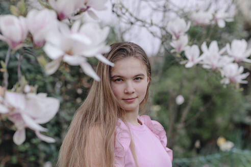 Blondes jugendliches Mädchen bei Magnolienbäumen im Park - OGF00879