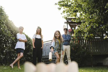 Girl playing molkky with family in back yard - MASF21513