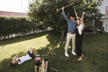 Fröhliche Eltern spielen Polo mit Kindern im Hinterhof - MASF21516