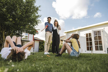 Mutter und Vater, die auf Kinder im Vorgarten zeigen - MASF21517