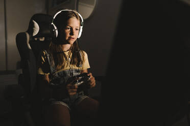 Girl playing video game at home during night - MASF21530