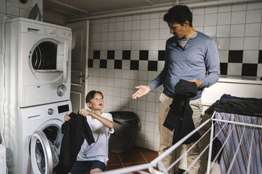 Son and father doing chores in utility room - MASF21531