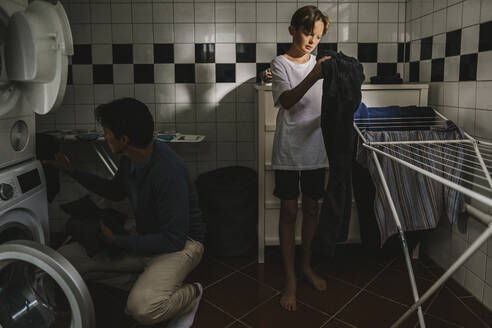 Vater und Sohn in der Waschküche beim Wäschewaschen - MASF21534