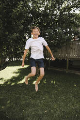 Cheerful boy jumping in back yard - MASF21547