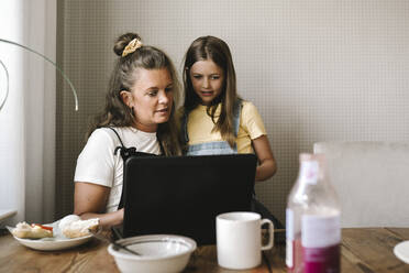 Mutter und Tochter benutzen Laptop am Esstisch - MASF21554