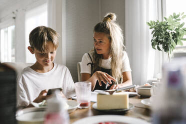 Mutter unterrichtet, während ihr Sohn zu Hause sein Smartphone benutzt - MASF21562