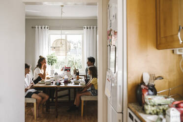 Glückliche Familie beim Frühstück, gesehen durch die Küchentür zu Hause - MASF21570