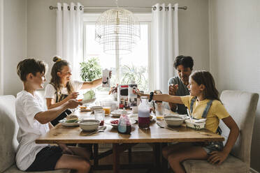 Eltern frühstücken mit ihren Kindern bei Tisch zu Hause - MASF21576