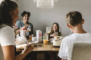 Happy family having breakfast on dining table at home - MASF21579