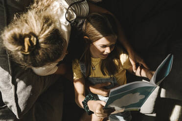 Tochter und Mutter lesen gemeinsam zu Hause ein Buch - MASF21597