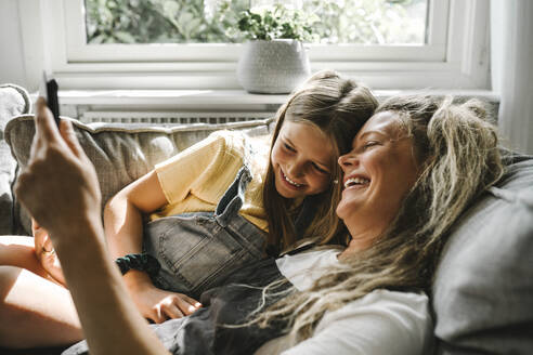 Lächelnde Mutter und Tochter benutzen ein digitales Tablet im Wohnzimmer - MASF21602