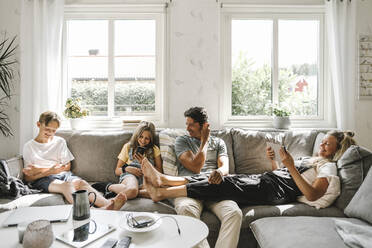 Happy family sitting on sofa in living room - MASF21605