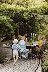 Smiling family looking at boy walking during dinner party in back yard - MASF21628