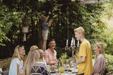 Boy talking with family during social event in back yard - MASF21631