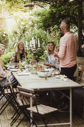 Vater im Gespräch mit der Familie beim geselligen Beisammensein auf einer Dinnerparty - MASF21633