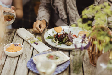 Reife Frau sitzt mit Essen auf dem Tisch - MASF21634