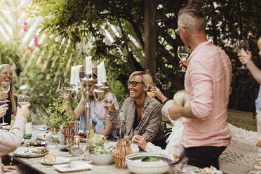 Cheerful family with toasting with wineglass at dinner party in front yard - MASF21635