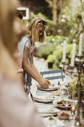 Teenage girl arranging plate on table for dinner party - MASF21642