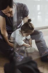 Baby-Sohn bindet Schnürsenkel mit Vater zu Hause sitzend - MASF21659