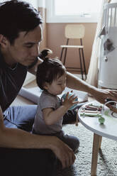 Vater und kleiner Sohn spielen mit Spielzeug im Wohnzimmer - MASF21673