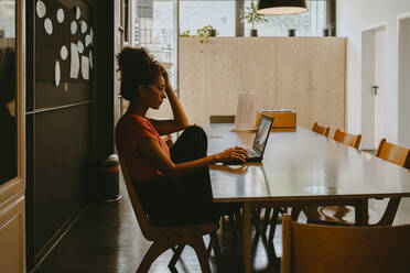 Female entrepreneur working on laptop in office - MASF21726