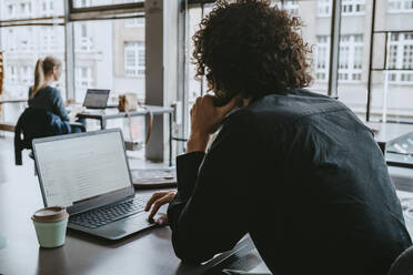 Geschäftsmann mit Laptop in einem Coworking Space - MASF21733