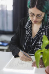 Young female artist working on sketch at studio - MGRF00161