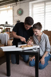 Young couple cutting pizza during relocation - CAVF92120