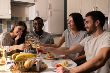 Multiethnische Freunde stoßen beim Abendessen mit Weingläsern an - CAVF92151