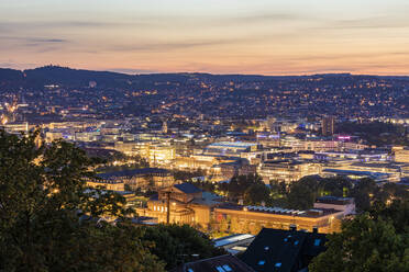 Germany, Baden-Wurttemberg, Stuttgart, Illuminated city center seen from top of Uhlandshohe hill at dusk - WDF06530