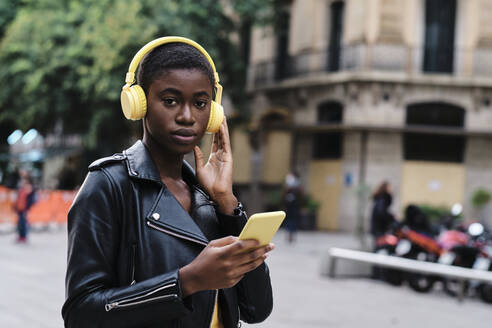 Woman listening music while standing in city - AGOF00025