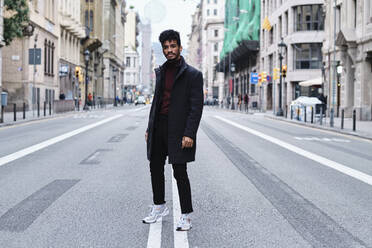 Young fashionable man staring while standing on road in city - AGOF00030