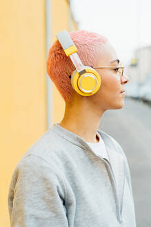 Porträt einer Frau mit kurzen rosa Haaren, die Kopfhörer trägt - ISF24344