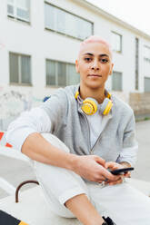 Porträt einer jungen Frau vor einem Gebäude, die ein Mobiltelefon benutzt - ISF24353