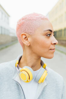 Porträt einer jungen Frau mit kurzen rosa Haaren, die Kopfhörer trägt - ISF24354