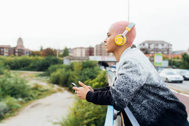 Frau auf Brücke, hört Musik über Kopfhörer - ISF24360