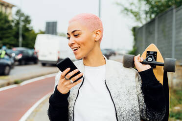 Skateboarder, der zu Fuß unterwegs ist und ein Mobiltelefon benutzt - ISF24361