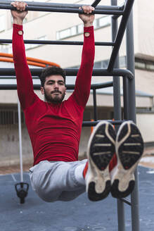 Junger männlicher Sportler beim Training an einem Sportgerät auf einem Trainingsplatz in der Stadt - JAQF00250