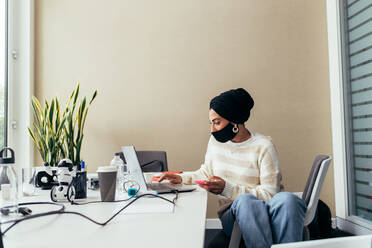 Woman working in office, wearing face mask - CUF56719