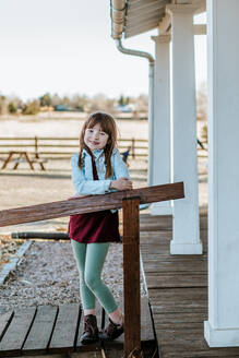 Happy young girl standing on patio smiling on a sunny day - CAVF92165