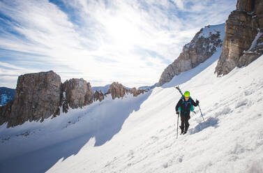 Man walking up steep snow section in California backcountry with skis - CAVF92217