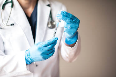 Doctor in white coat drawing vaccine into a syringe for injection. - CAVF92223