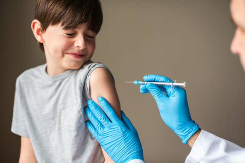 Nervous looking child getting vaccinated by doctor holding a needle. - CAVF92226