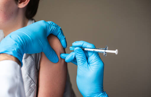 Close up of child getting vaccinated by doctor holding a needle. - CAVF92228