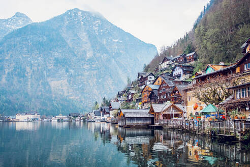 Malerische Landschaft mit traditionellen Wohnhäusern und der berühmten evangelischen Pfarrkirche von Hallstatt am Seeufer, umgeben von Bergen in Österreich - ADSF20646