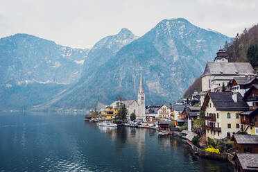 Picturesque landscape of traditional residential houses and famous Lutheran Parish Church of Hallstatt located on lake shore surrounded by mountains in Austria - ADSF20647