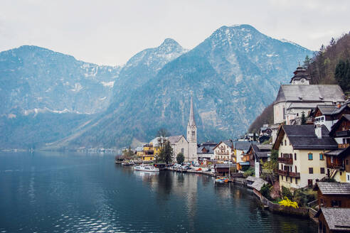 Malerische Landschaft mit traditionellen Wohnhäusern und der berühmten evangelischen Pfarrkirche von Hallstatt am Seeufer, umgeben von Bergen in Österreich - ADSF20647