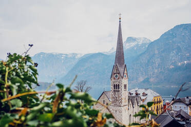 Malerische Landschaft mit traditionellen Wohnhäusern und der berühmten evangelischen Pfarrkirche von Hallstatt am Seeufer, umgeben von Bergen in Österreich - ADSF20648