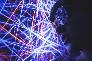 From below of female in trendy sunglasses illuminated by red and blue abstract neon lights in darkness - ADSF20650