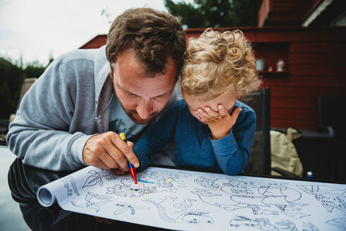 Father and child coloring together outside during lockdown - CAVF92311